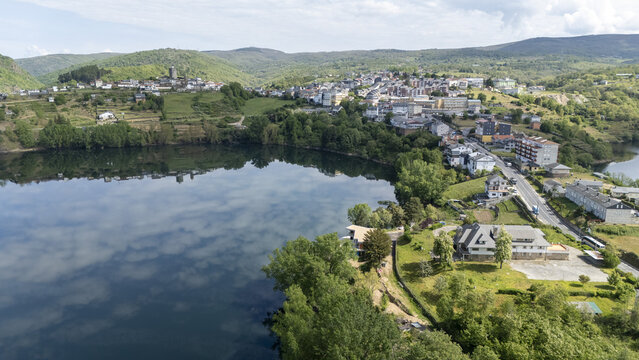 Aerial view of the town with its historic buildings and tower overlooking the calm waters of the Bibei reservoir under a cloudy sky in Viana do Bolo, Province of Ourense, Spain.