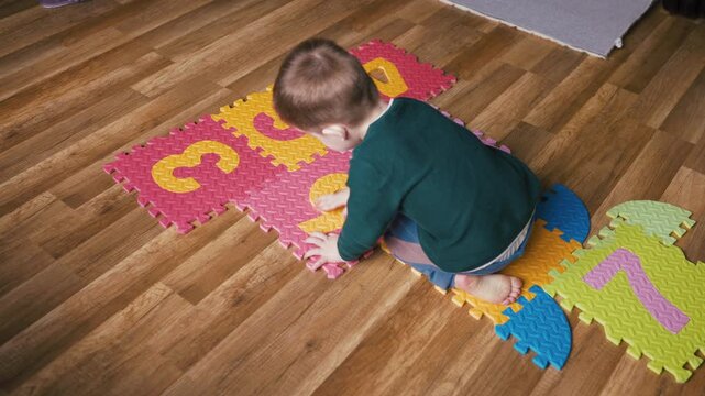 Little boy assembling a colorful foam number puzzle mat on the floor