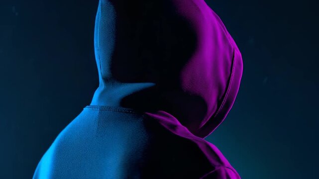 Hooded anonymous figure in blue and purple neon lighting, dark cyber security portrait with hidden identity and mysterious digital mood