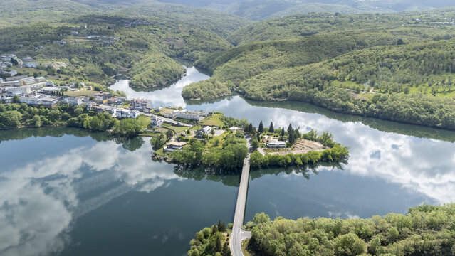 Aerial view of the town of Viana do Bolo situated on a peninsula surrounded by water with a bridge and lush green hills under a cloudy sky Viana do Bolo, Province of Ourense, Spain.