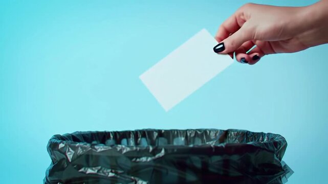hand throwing paper into trash can.