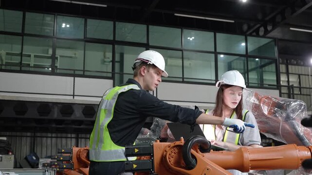 Factory workers collaborating on robotic arm installation and programming