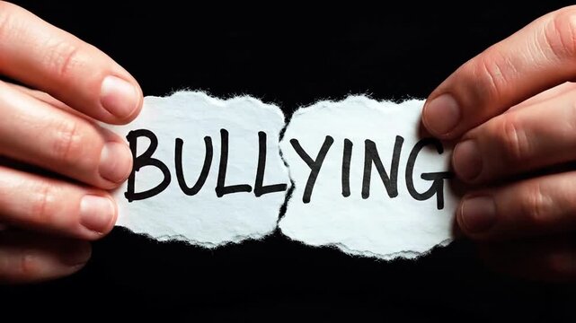 Hands tearing apart paper with bullying text.