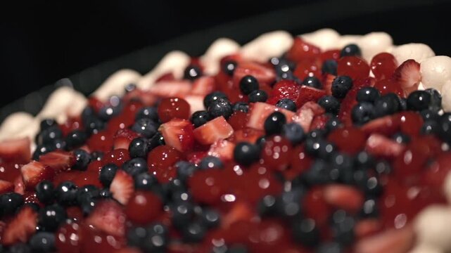 Berry tart dessert with strawberries (Fragaria &times; ananassa) and blueberries (Vaccinium corymbosum) covered in glossy glaze with shallow depth of field and strong bokeh, extreme macro shot, pan reveal