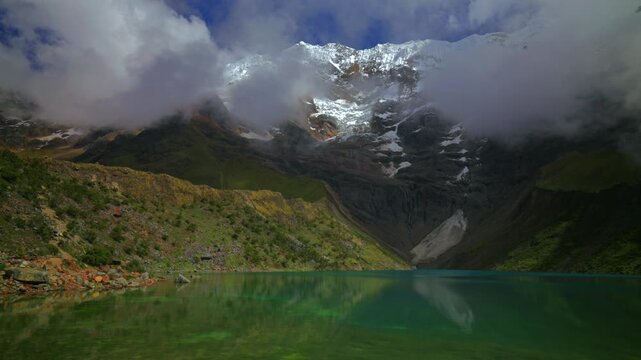 Turquoise clear glacial water Peru's Laguna HumantayLake Humantay rocky shoreline Peruvian Andes Mount Humantay Peru nature landscape view snow covered peaks fog clouds motion morning sunny static
