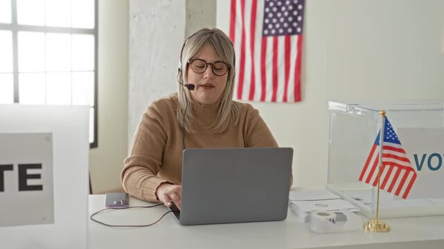 Woman typing on laptop with headset microphone, hand on keyboard at a voting station inside a building; civic duty.