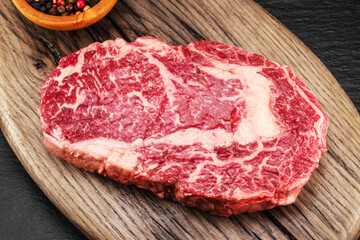 Fototapeta premium Raw ribeye steak on a wooden board. Top view. Macro.