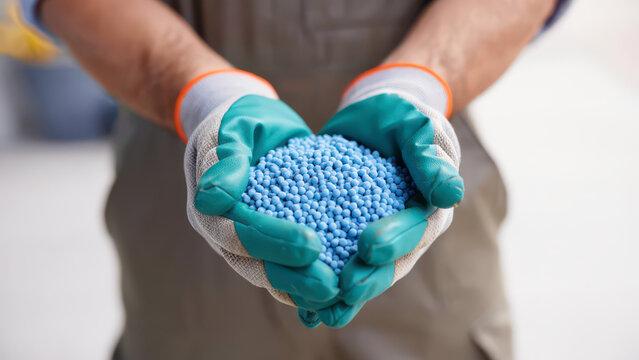 Worker holding blue granulated mineral fertilizer in palms, professional soil enrichment for agriculture, chemical plant nourishment, crop yield optimization, industrial farming resource banner