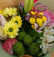 Naklejka premium Vista de cerca de un colorido ramo con diversas flores y decorado con corazones de madera, para regalar en festividades y celebraciones 