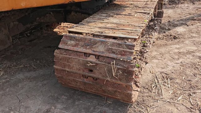 Close-up of dirty excavator tracks covered in mud.