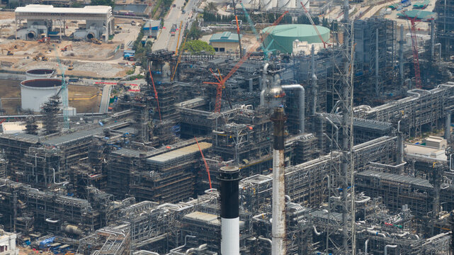 Aerial view of Bangchak Sriracha Refinery with complex piping systems, industrial towers, and construction cranes in Si Racha District, Chon Buri, Thailand.