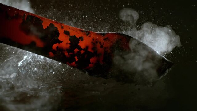Blacksmith puts the red-hot forged metal part into the water . Super slow motion filmed on high speed cinematic camera at 1000 fps