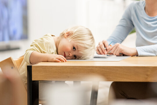Exhausted toddler falling asleep during art lesson with mom