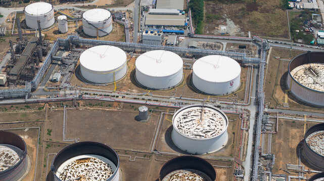 Aerial view of Bangchak Sriracha Refinery with large white storage tanks, intricate pipeline networks, and industrial infrastructure Si Racha District, Chon Buri, Thailand.