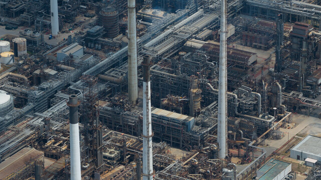 Aerial view of Bangchak Sriracha Refinery with its complex network of industrial pipes, tall chimneys, and steel structures in Si Racha District, Chon Buri, Thailand.