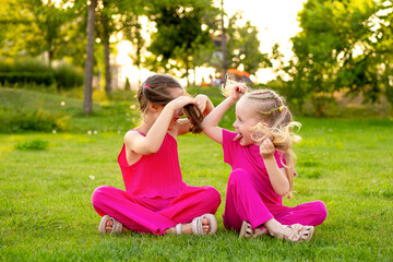 Fototapeta premium children in the park in summer, little girls walking and having fun on a green lawn, playing, summer holidays