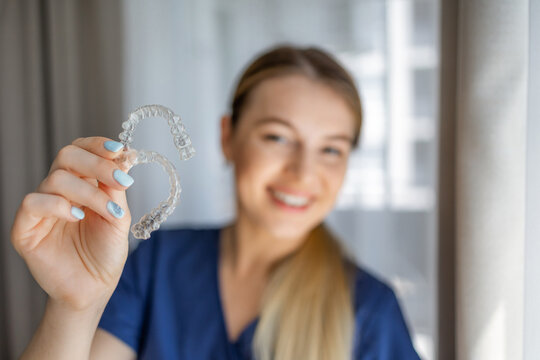 Smiling orthodontist holding a clear aligner tray in a dental consultation setting