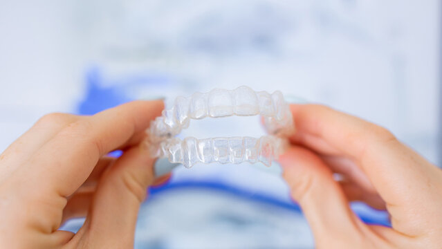 Clear aligners for orthodontic teeth straightening held by patient in a clinic