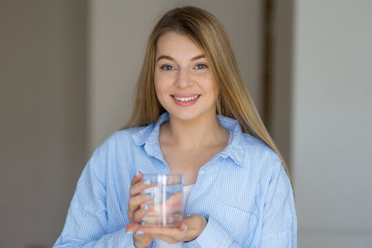 Smiling woman holding a glass of water in a bright room