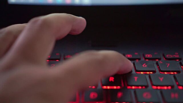 Typing hands on number laptop keyboard with LED lighting, programming and productivity concept.