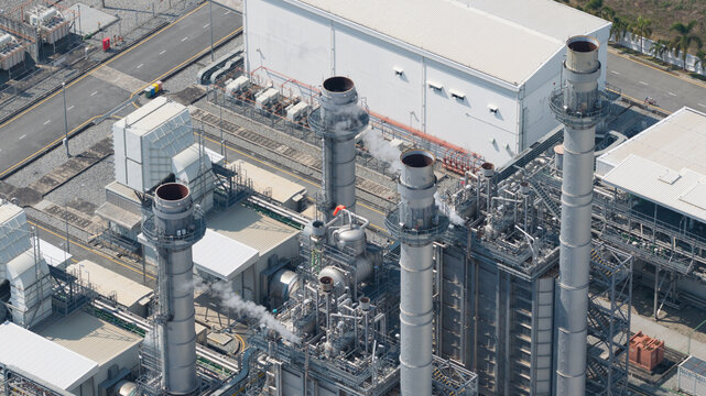 Aerial view of Amata B.Grimm Power Rayong 5 power plant with tall smokestacks emitting steam and industrial infrastructure in Map Yang Phon, Rayong, Thailand.