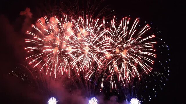 Red white and blue fireworks exploding in slow motion in the night sky during Fourth of July celebration. Patriotic festive background with copy space for text. Independence Day holiday US