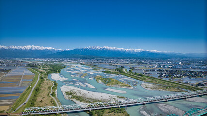 五月、田植えの季節の黒部川扇状地周辺を黒部川河口から見渡した風景 © crossover.japan