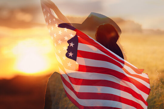Woman in cowboy hat silhouette holds the American Flag inside her head. 4th July celebration concept.