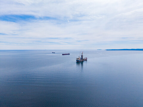 Oil tanker travels across the open sea while other vessels are present in the distance during daytime