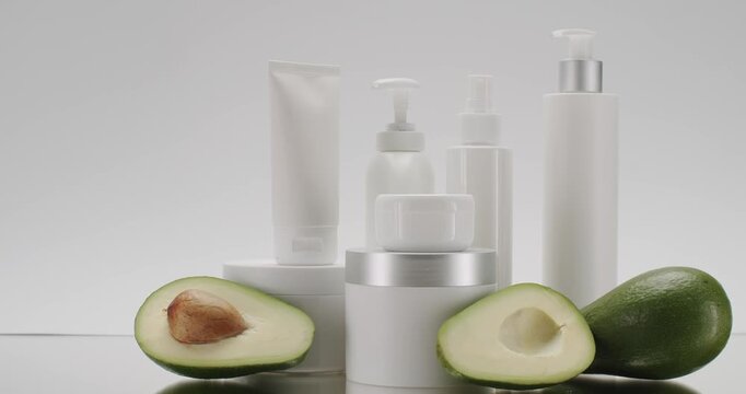 White Bottle and tubes with avocado for cosmetics on a white background in studio, scrub, tonic, body care. Jars, bottles, tubes with avocado for cosmetics and Beauty treatment on a white background