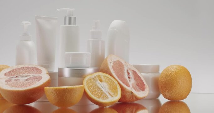 White Bottle and tubes with Citrus Grapefruit and orange Fruits for cosmetics on a white background in studio. Cosmetics oils based on natural ingredients, scrub, body care. Camera Trucking in left