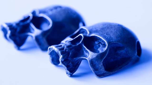 Macro shot of creepy metallic humanoid skulls bathed in blue light. Spooky background template for extraterrestrial mysteries, Roswell conspiracies, and nightmare concepts. Photo