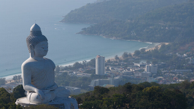Aerial view of the majestic Big Buddha statue on a lush hilltop overlooking the turquoise waters and sandy coastline of Karon Beach in Tambon Karon, Chang Wat Phuket, Thailand.