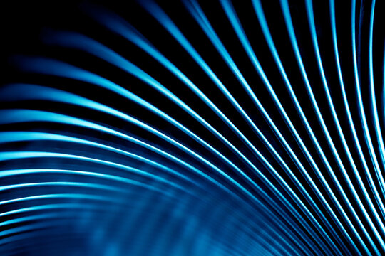 Close-up of curved metal lines glowing in neon blue. Perfect modern backdrop for technological concepts, futuristic designs, and industrial business presentations. Photo