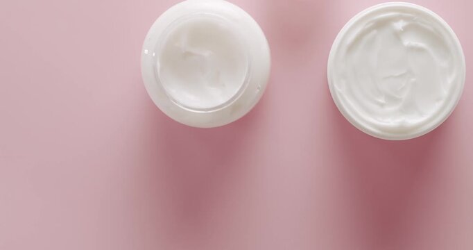 Cosmetics oil based on natural ingredients, scrub, tonic, body care, skin care. Cosmetic jar with cream. Different cosmetic bottles. Jars cream for Beauty treatment, top view on a pink background.