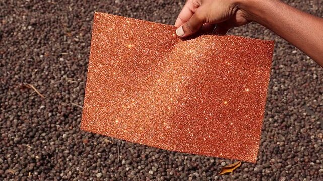 Orange color glitter paper also called as shining paper emitting sparkles of light when exposed to outdoor sunlight