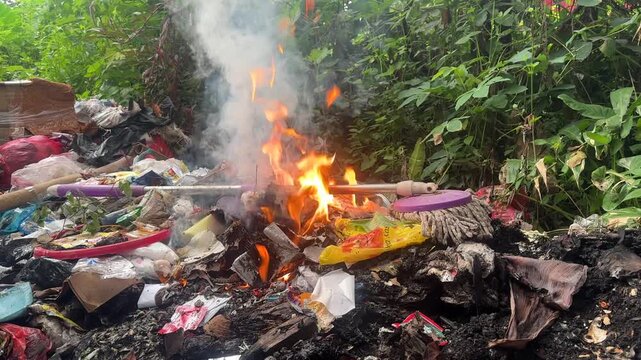 Burning pile of plastic waste and garbage in nature environment