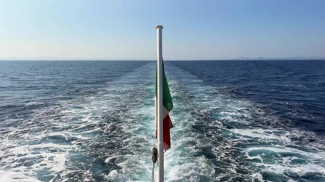 A view of the wake left by a moving ship, seen from the stern. A flag is waving in the centre of the frame