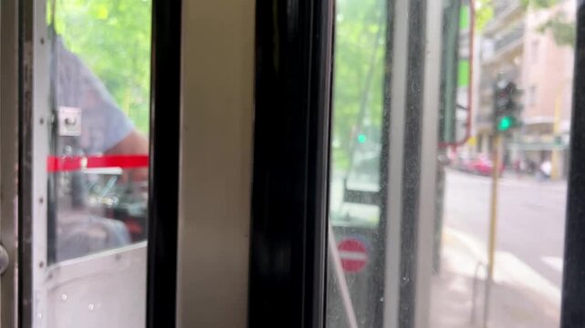 View from the driver's cab of a tram in Milan. Tram stops at the stop and opens the door