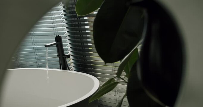 A stylish glimpse into modern home design featuring a round table, open blinds, and lush greenery. Ideal for themes of interior design and peaceful living spaces.