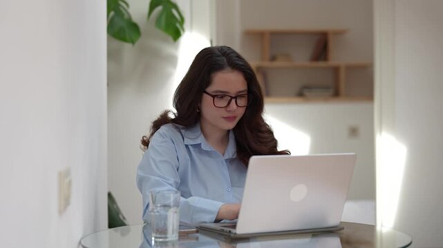 Tired woman sitting at table with laptop, looking unmotivated during remote work. Concept of burnout, overwork and mental fatigue from prolonged computer use. Digital stress while working from home.