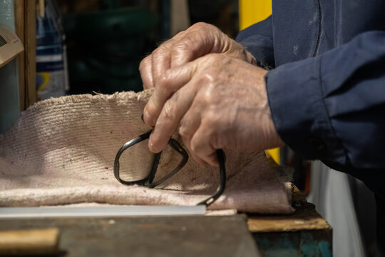 Skilled artisan hands carefully assembling eyewear frames on a workbench, showcasing traditional craftsmanship, precision, and quality maintenance in professional optical service