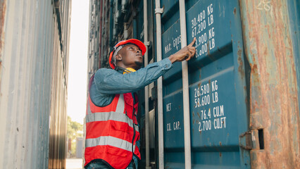Worker container industry logistics shipping safety warehouse transport cargo port Confident male worker wearing safety vest and helmet stands between large cargo container industrial shipping © chokniti