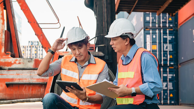 Asian worker logistics engineer safety vest hard hat container teamwork tablet clipboard discussion inspection cargo shipping port dock warehouse supervisor foreman transport industry industrial