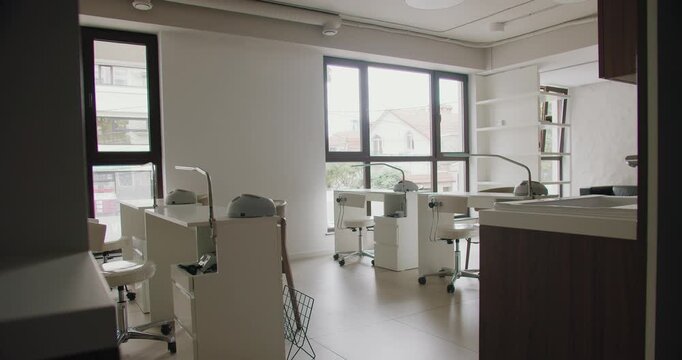 Explore a spacious nail salon featuring stylish design, modern furniture, and ample natural lighting through large windows. Modern Nail Salon Interior with Stylish Stations and Bright Windows