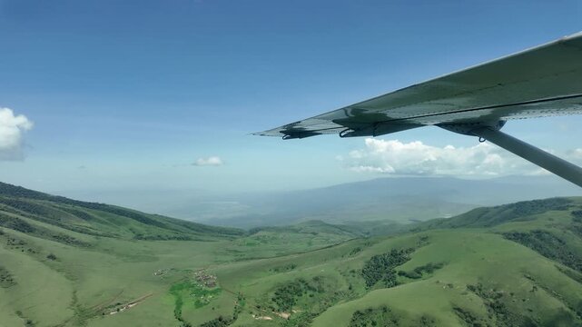 aerial footage of the maasai region with green hills and settlements from a small plane