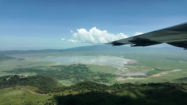 flying over the lush green ngorongoro crater with airplane wing visible