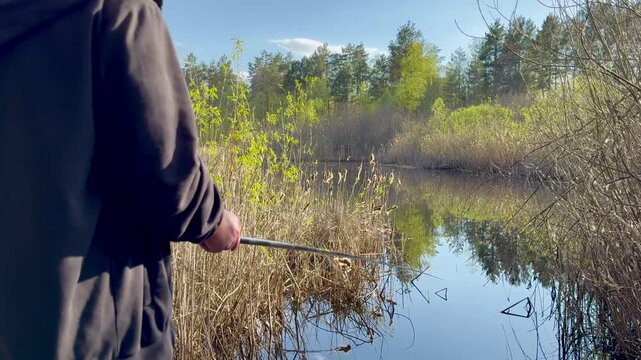 A fisherman watches the float on the water, then pulls the fishing rod out of the water. There is no fish on the hook