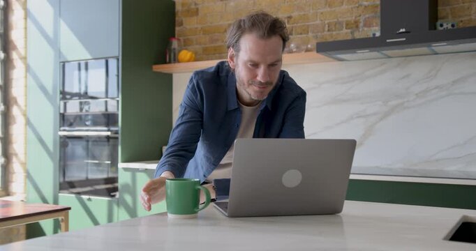 Businessman working on laptop with coffee mug in Kitchen