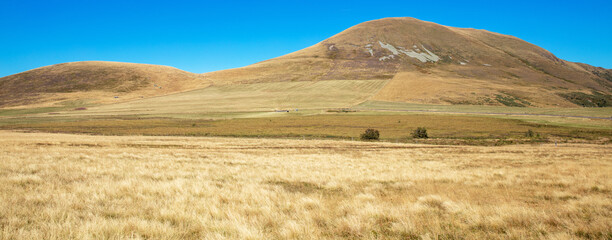 Obraz premium panoramic wide angle view of dry golden hills and mountains under a clear blue sky in autumn